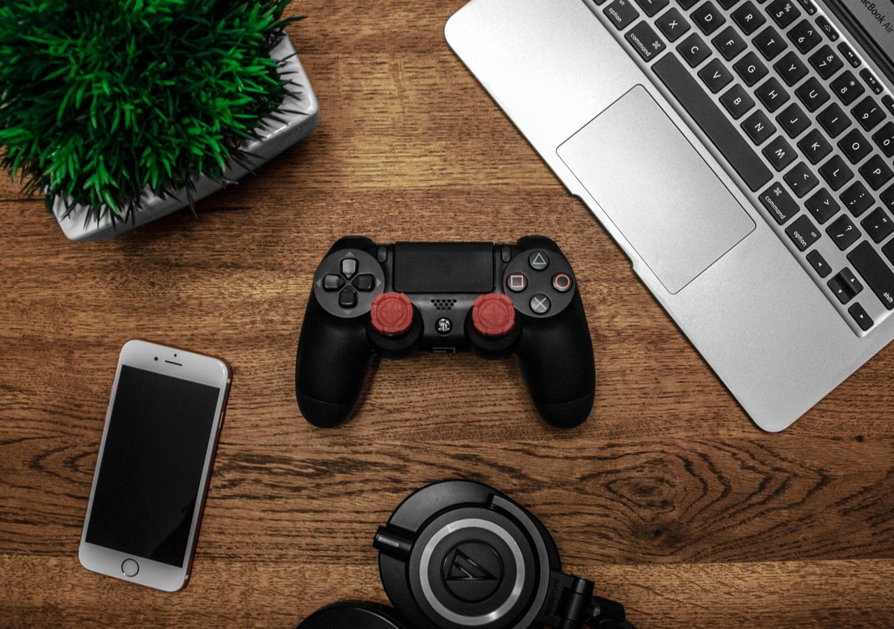 The Art of Drawing Readers In: Your attractive post title goes here A flat lay photo showcasing a gaming console, laptop, smartphone, and headphones on a wooden tabletop.